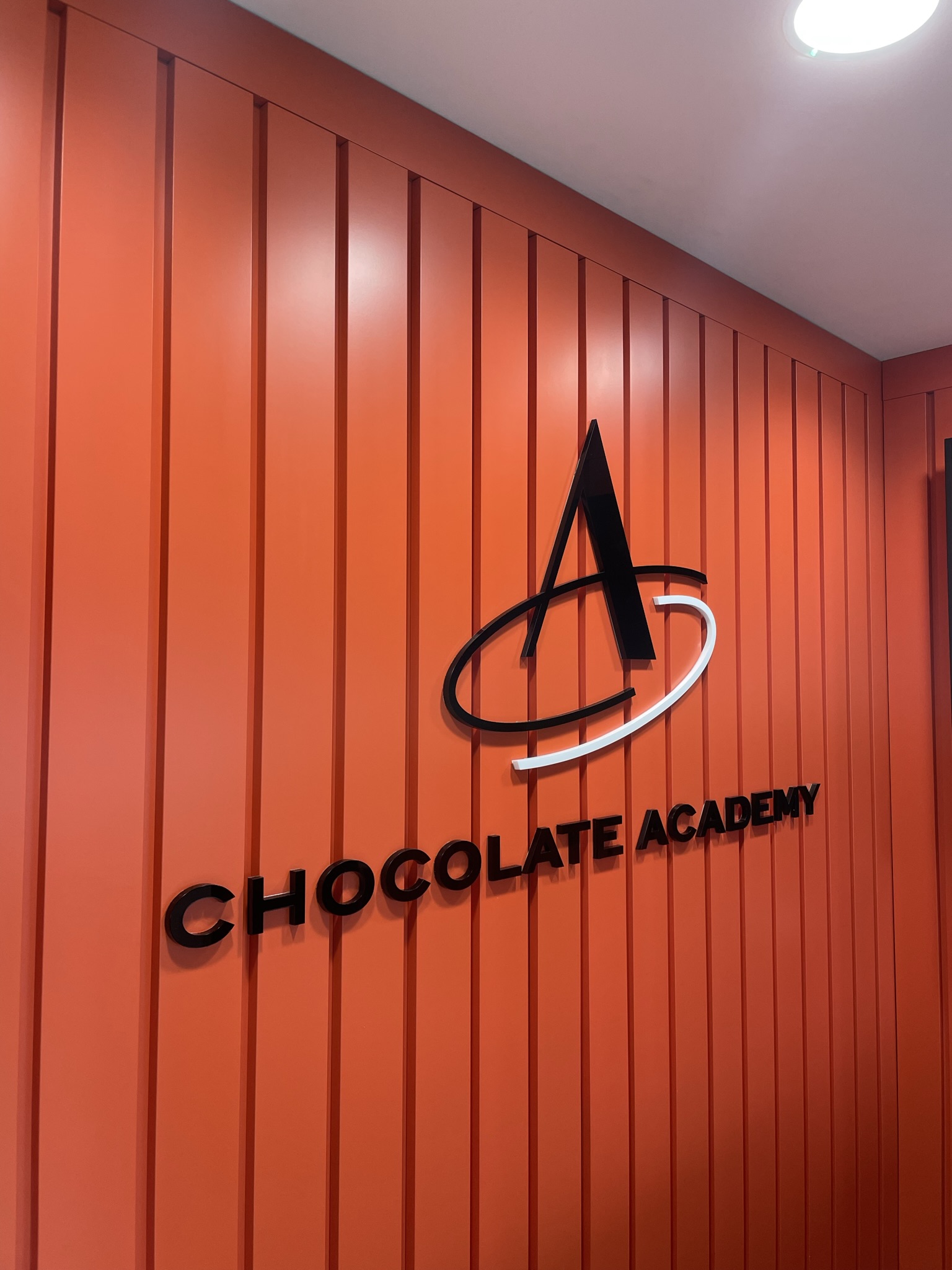 Orange slatted wall with Chocolate academy lettering