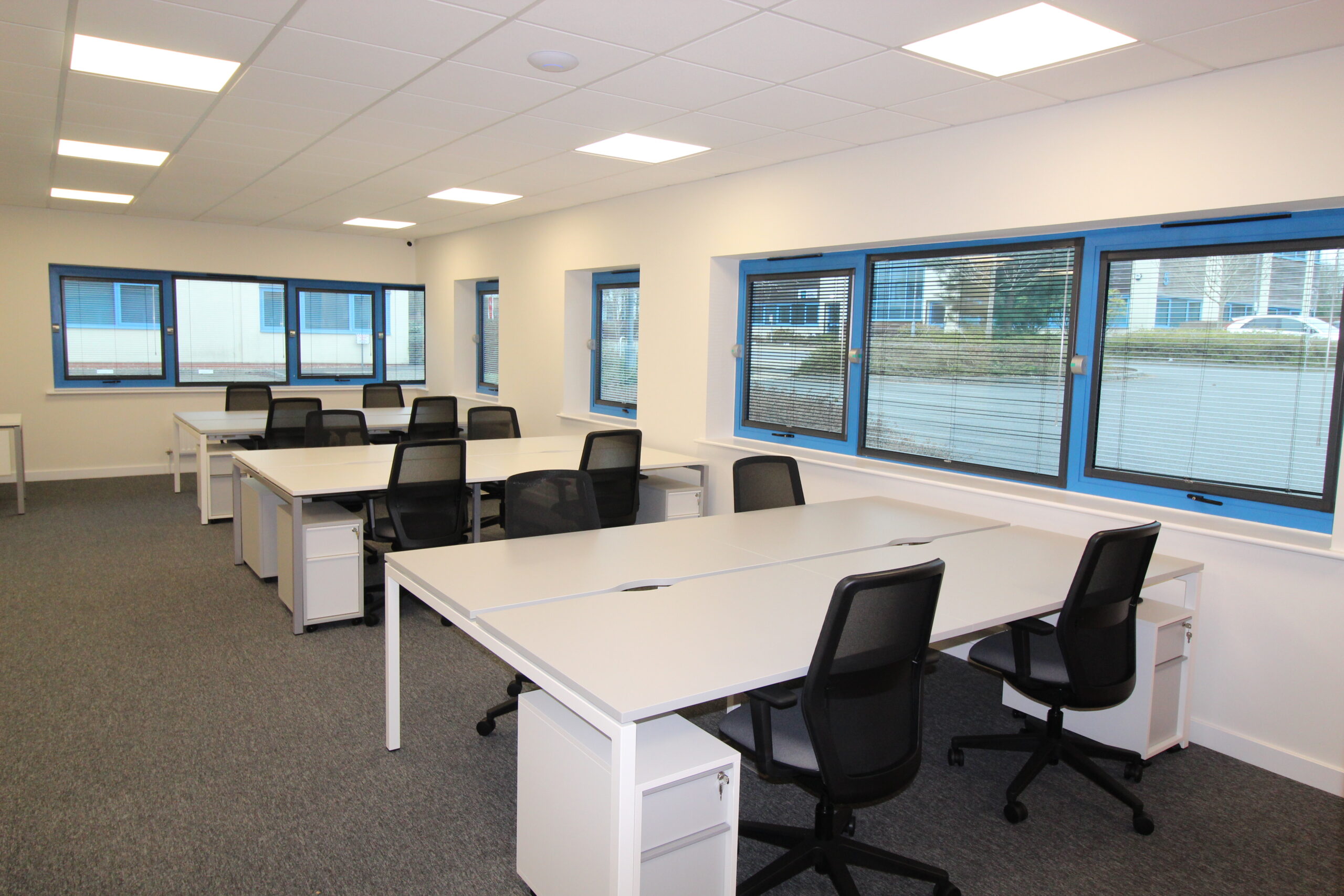 Office with suspended ceiling, LED lighting, desks and black chairs