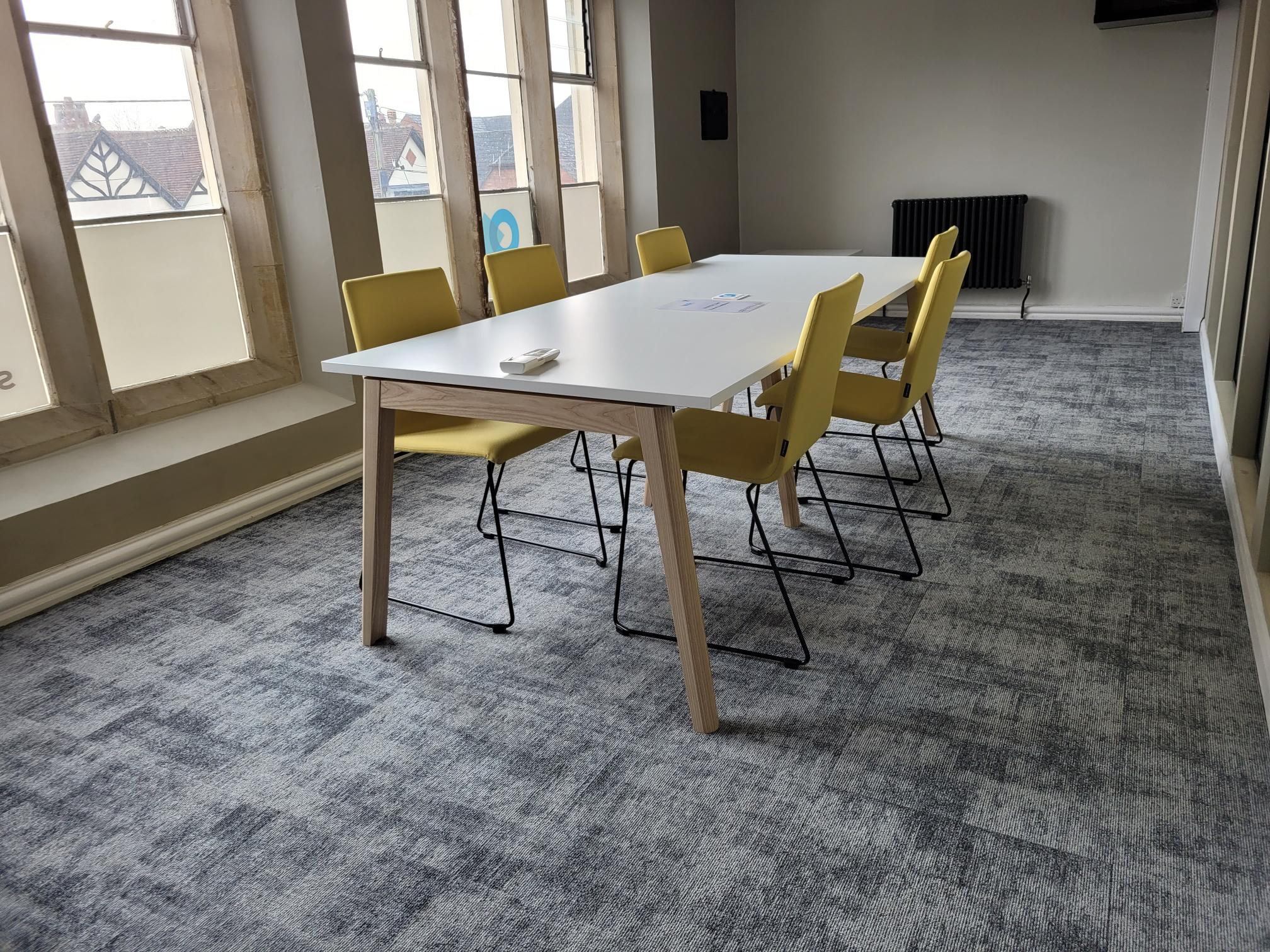 White boardroom table with yellow chairs around the table