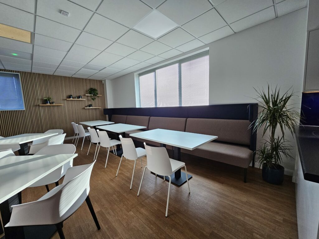 Office break out area with timber slatted feature wall, white tables and chairs