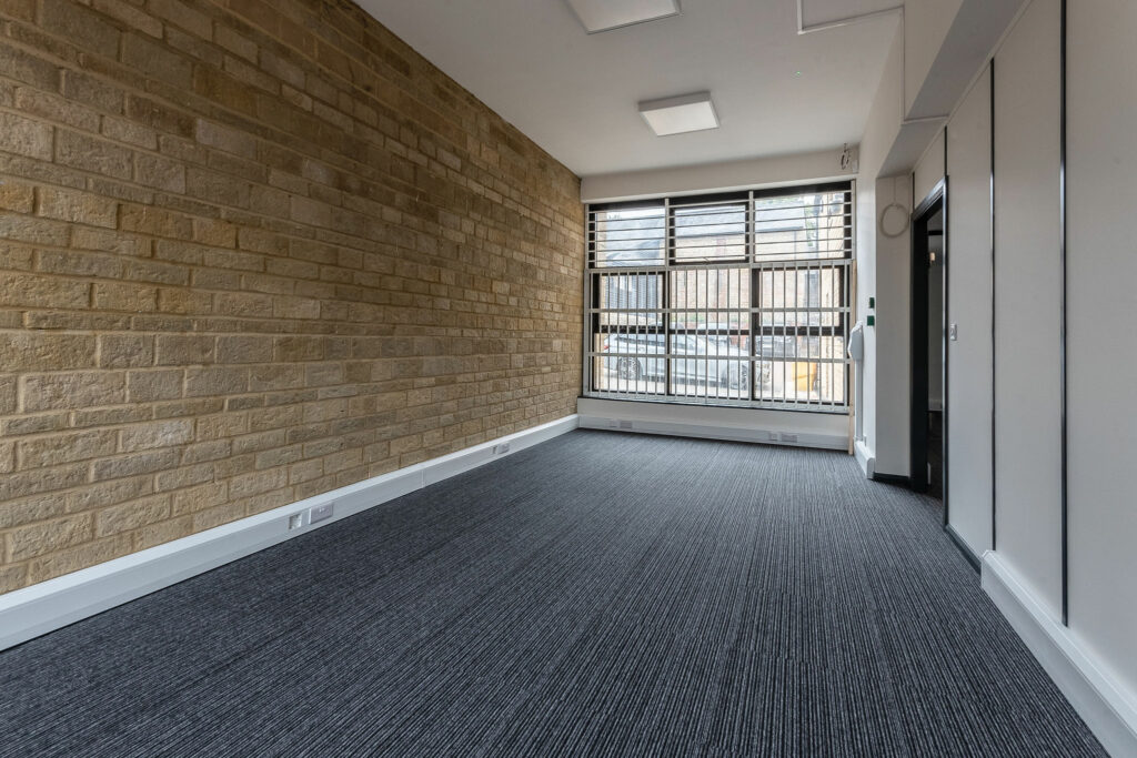 Individual office space with exposed stone wall and grey carpet