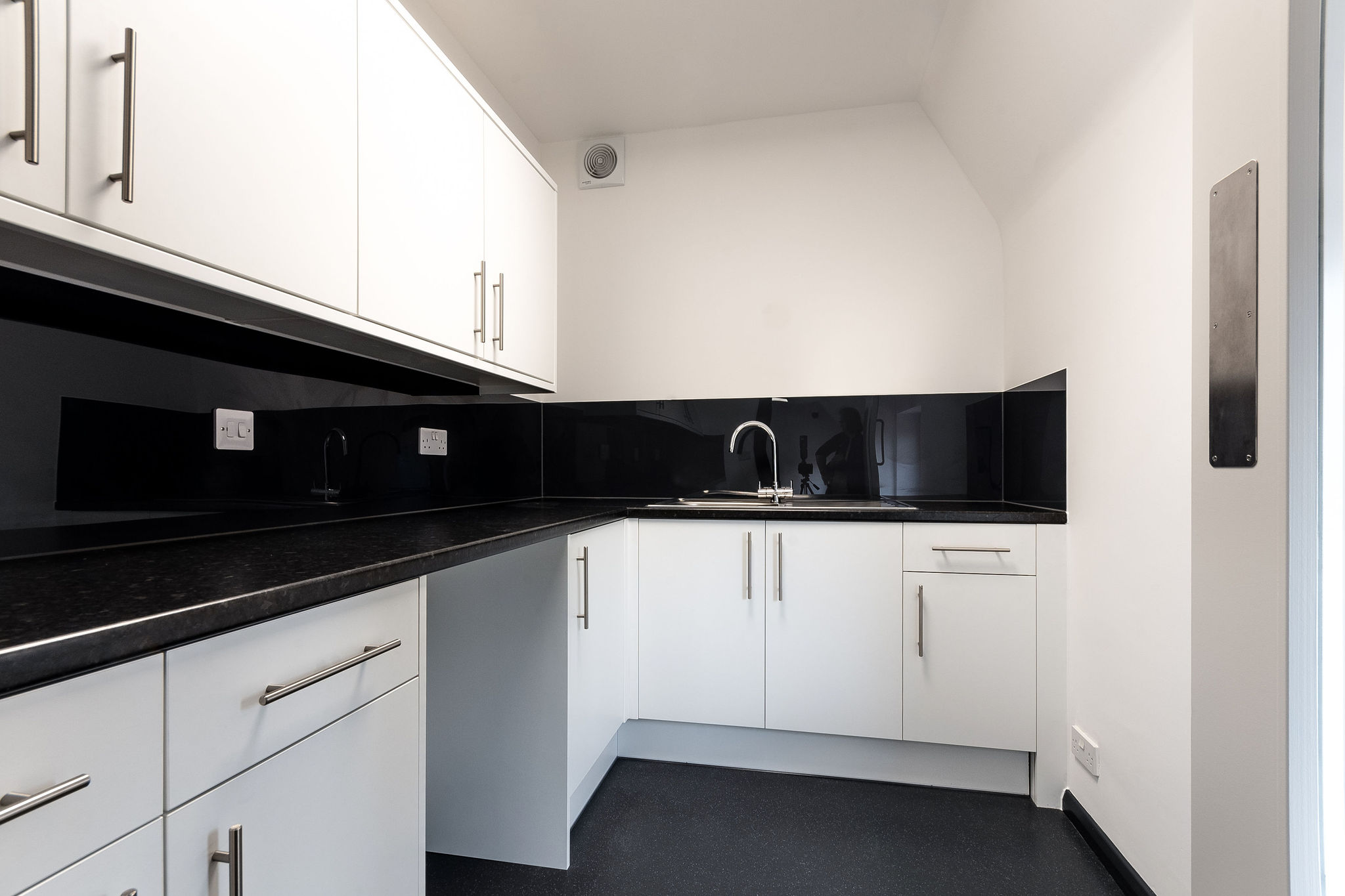 White kitchen units with black worktop and splashback