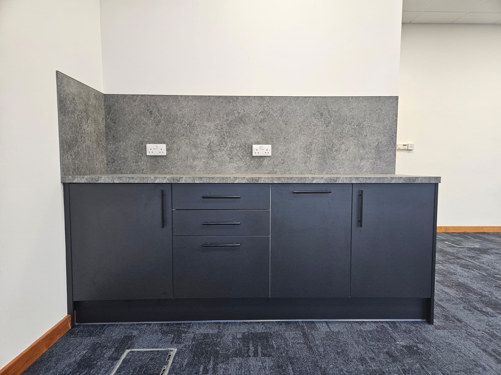 Kitchen units and integrated fridge within open plan office