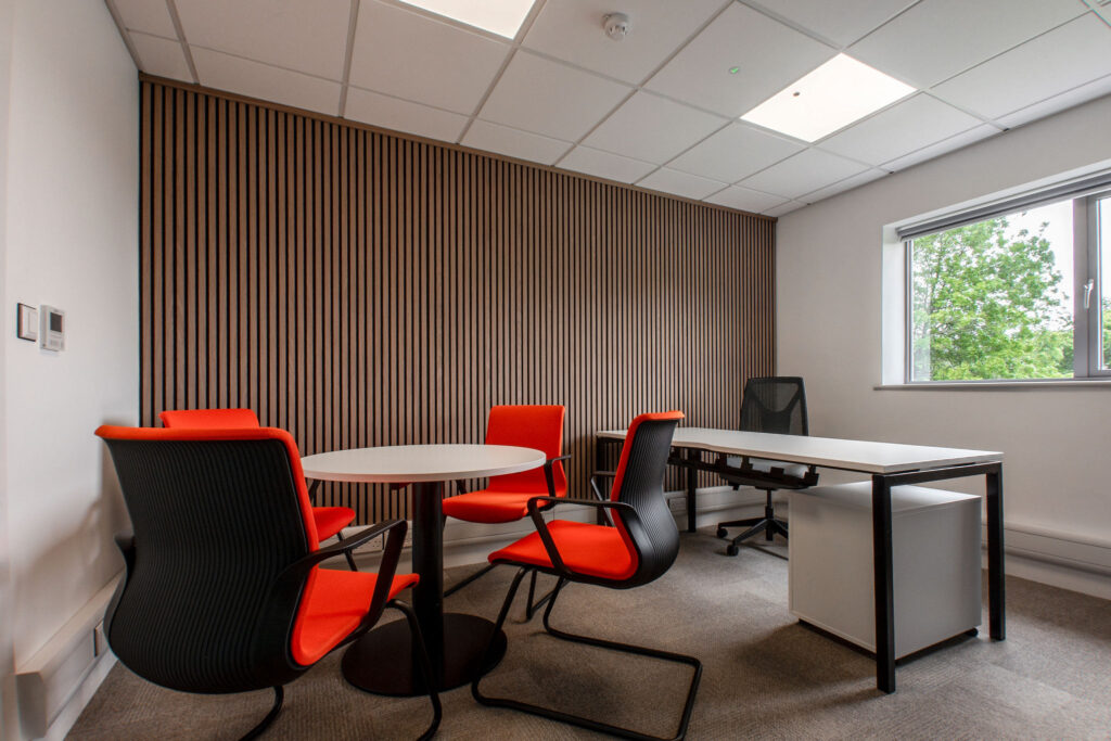 Small round meeting table and 4 black chairs with bright orange seat pads