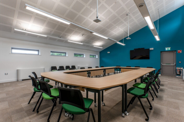 Mix of rectangle and deltoid shape desks and green padded chairs on castors
