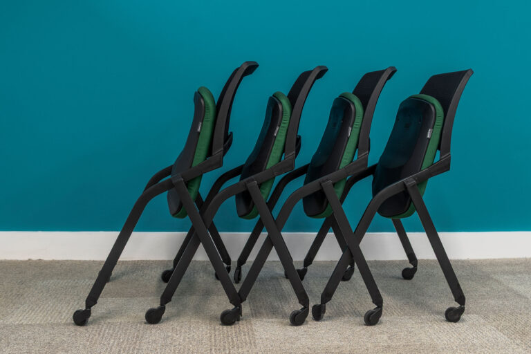 Side angle image of 4 folder black chairs with green seat pads