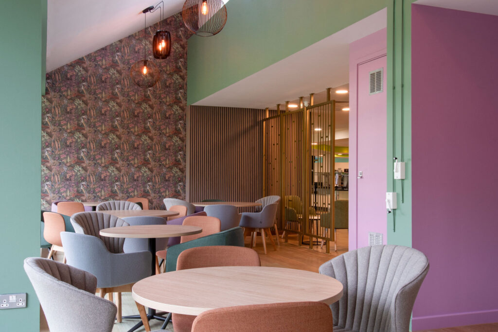 Coffee tables with chairs in foreground and floral wallpapered feature wall
