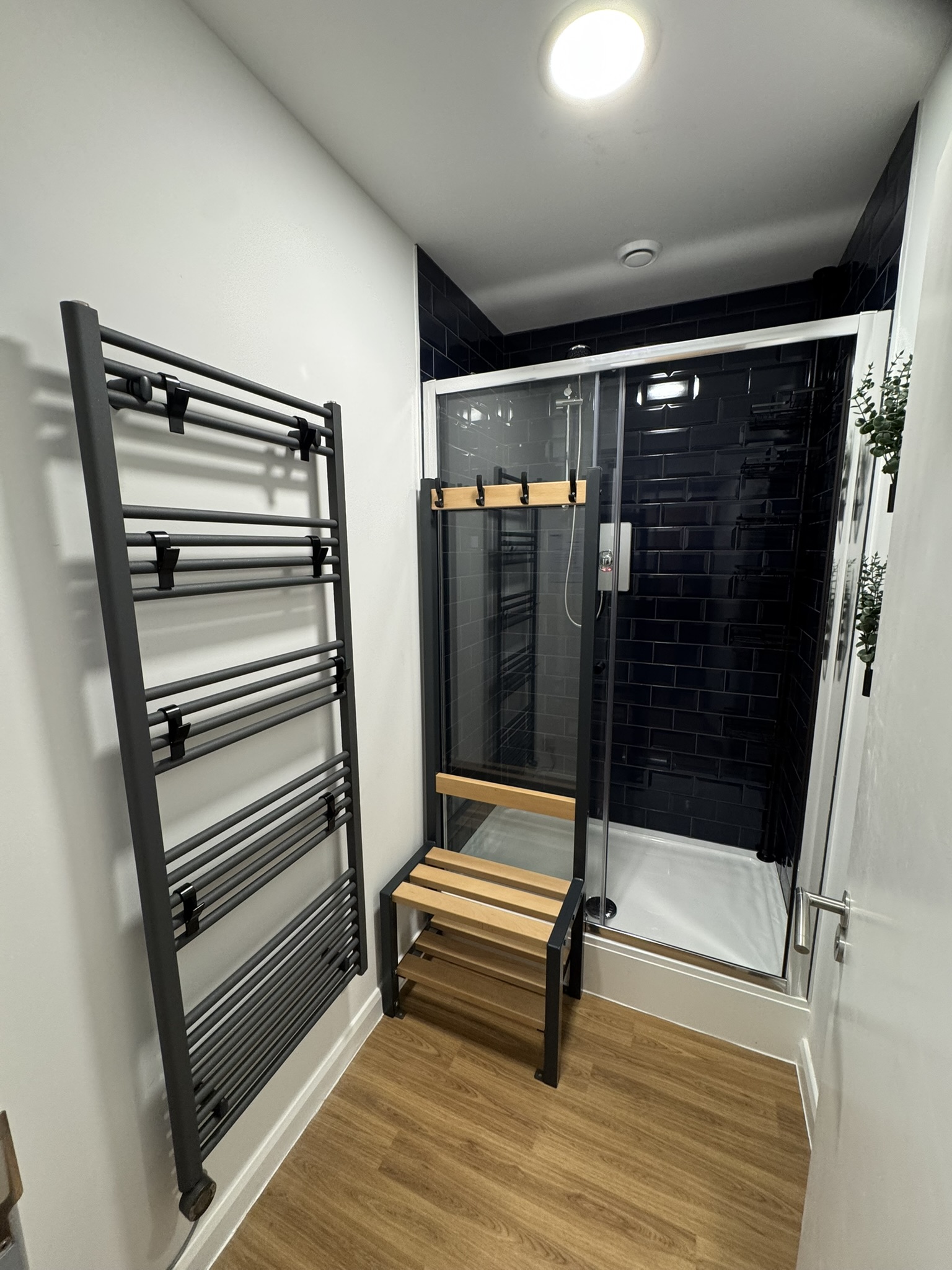 Shower area with tall towel rail and slatted seating bench
